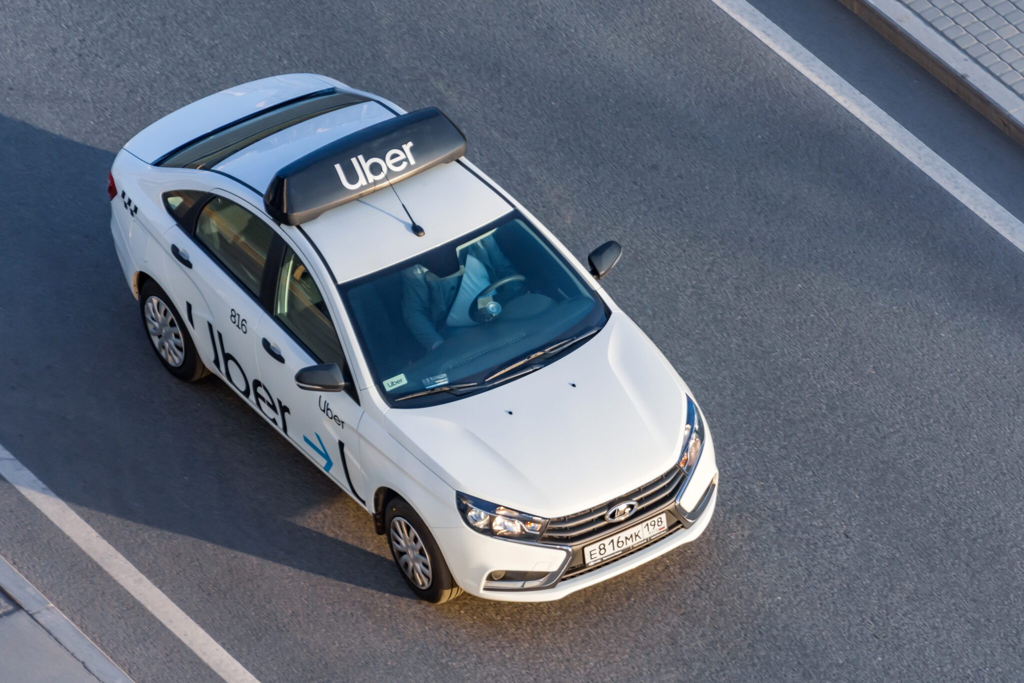 White passenger white car Uber Taxi rides on the highway aerial view. Russia, Saint-Petersburg. 14 april 2020.