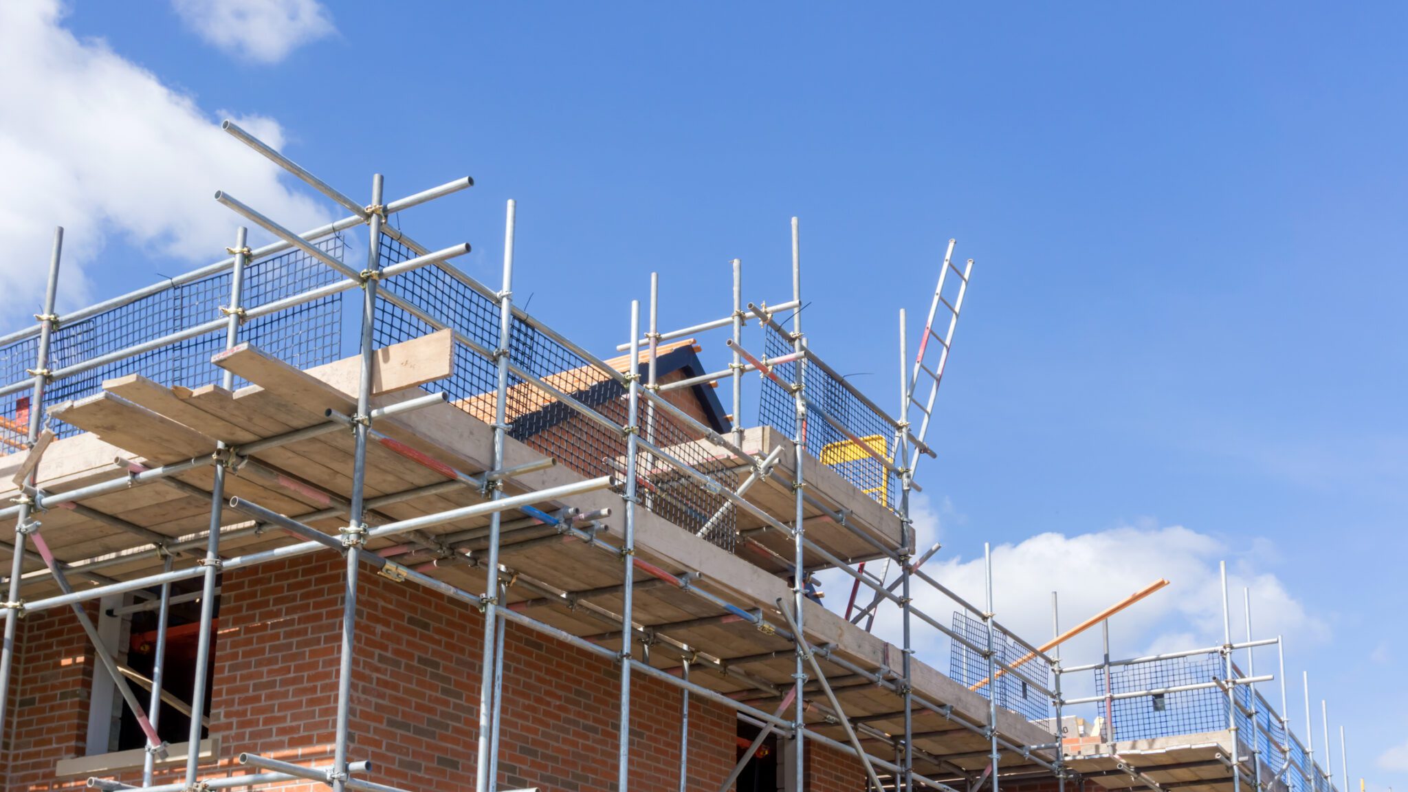 Top Corner of House With Scaffolding Around the Outside On A Clear Day