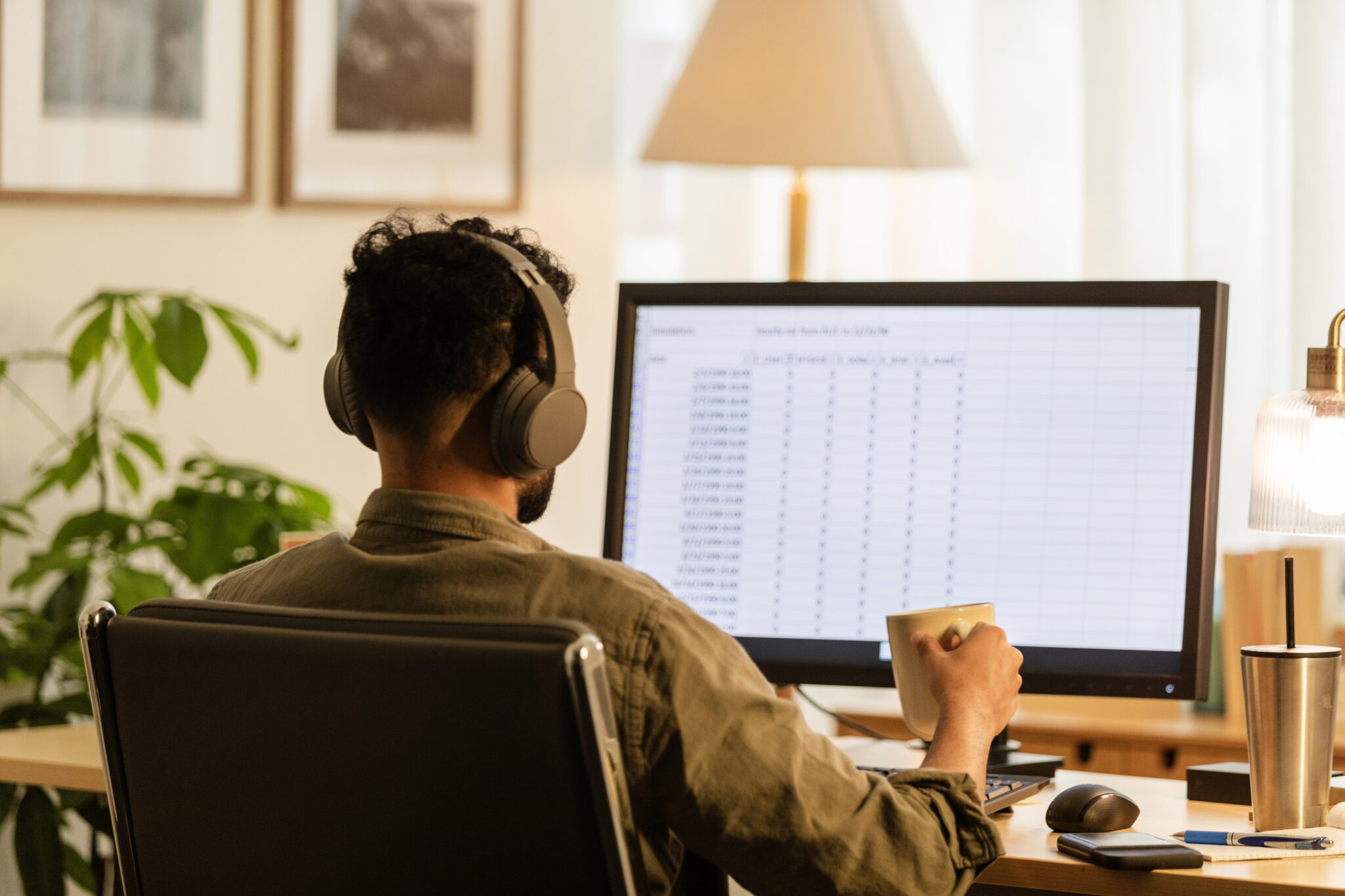 Unrecognizable young adult male works from home at the computer