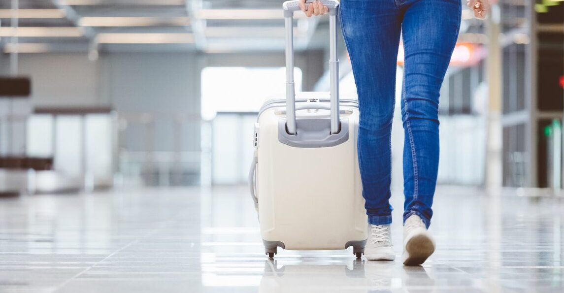 Woman walking with suitcase at airport terminal