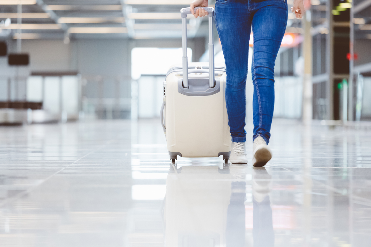 Woman walking with suitcase at airport terminal