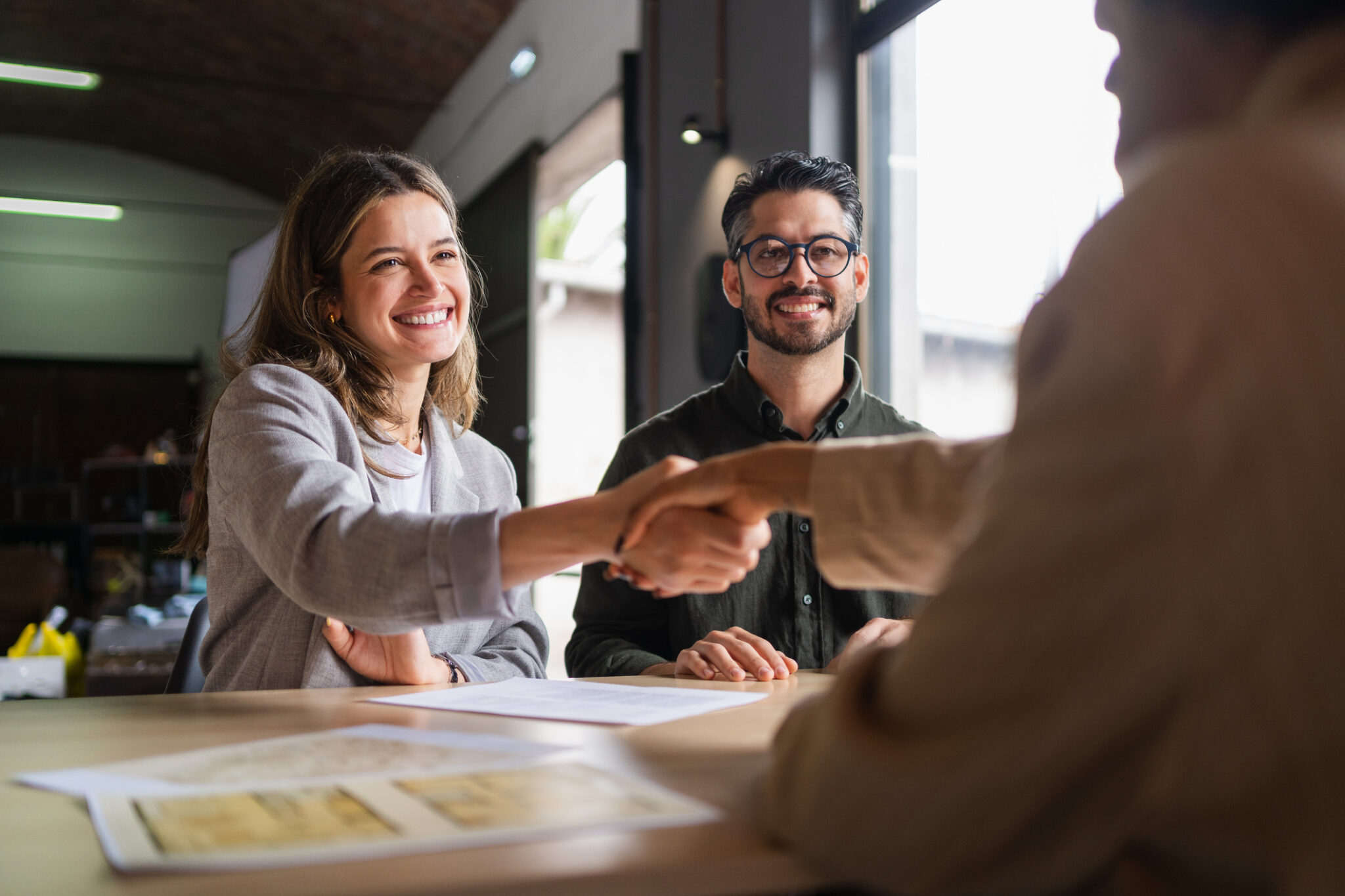 Business partners shaking hands in an office after finalizing a contract, celebrating a successful agreement and fostering collaboration