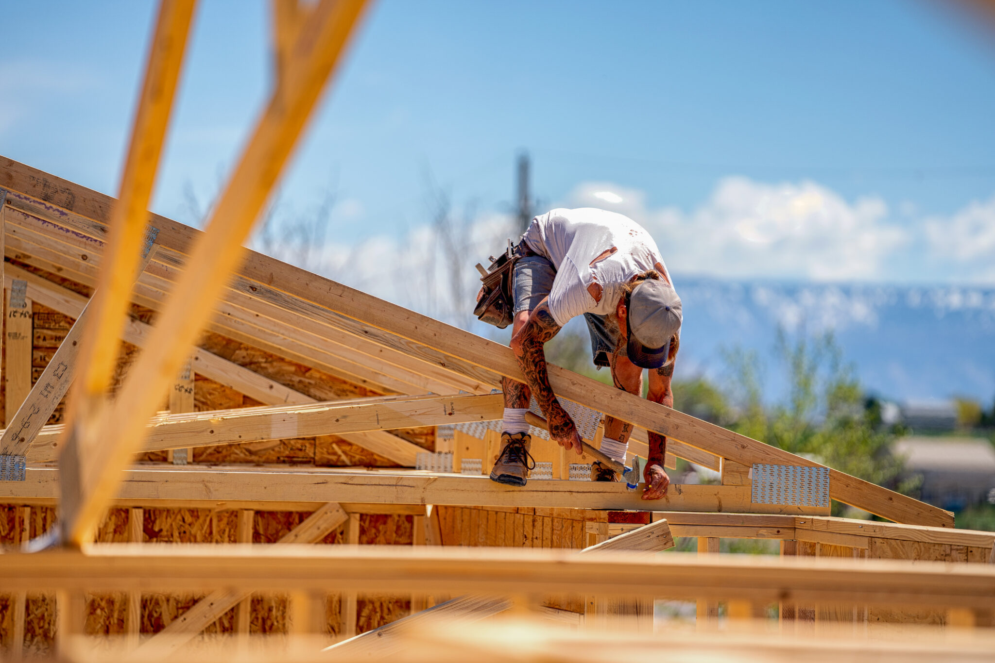 Rugged Carpenter on a Framing Crew Setting Trusses on a New Home