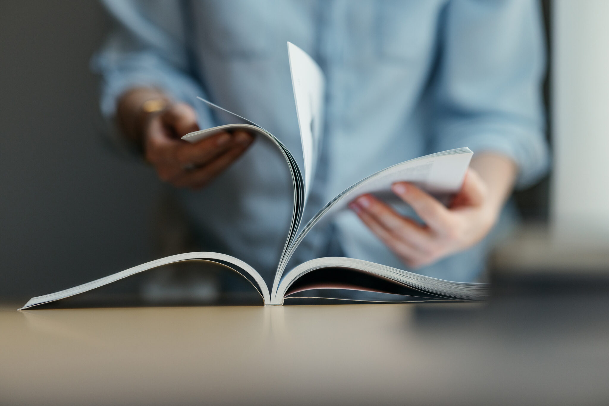 An Unrecognizable Woman Turning Pages Of A Book In A Library