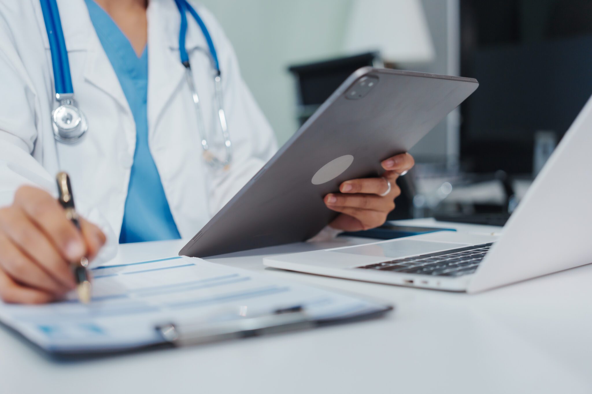 Asian female doctor is reviewing medical records, working on a computer, planning treatment, giving online consultations, and explaining medications to patients via a medical video call in a clinic