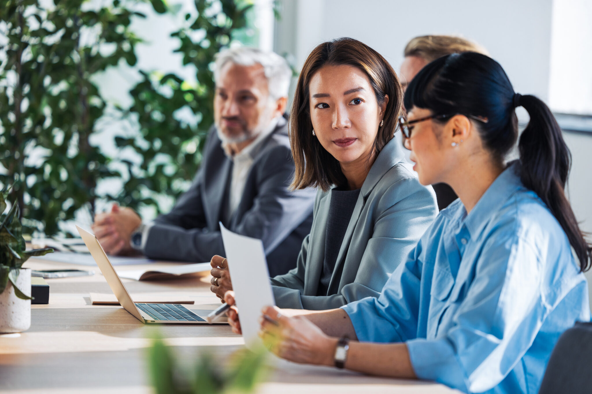 Business Meeting With Diverse Team Members Discussing Documents In A Modern, Collaborative Office